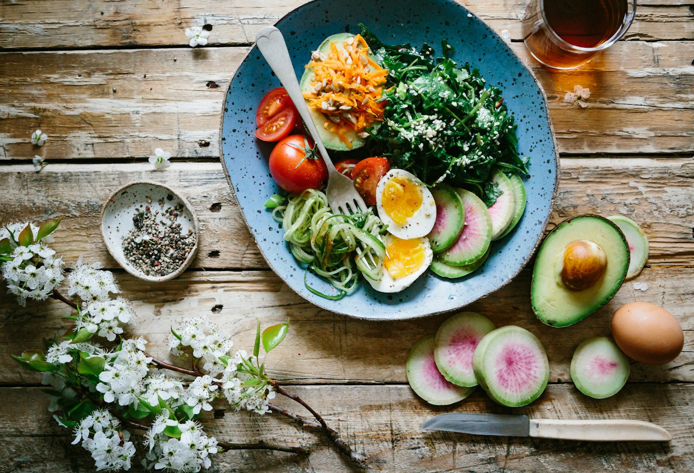 Bol con verduras, huevo cocido y aguacate sobre una mesa de madera